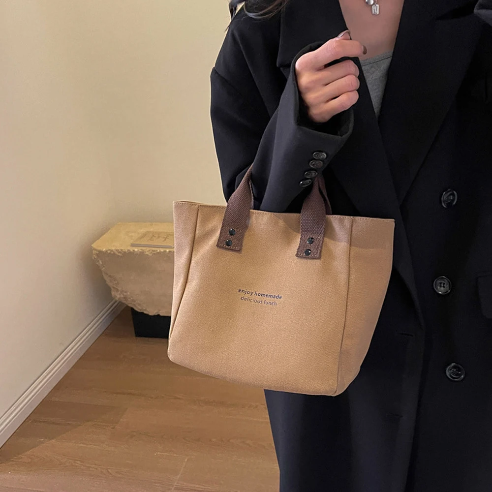 A Casual Canvas Tote Bag with a Bell Pendant and Zipper Closure; This Stylish and Durable Tote Bag Is Perfect for School and Work