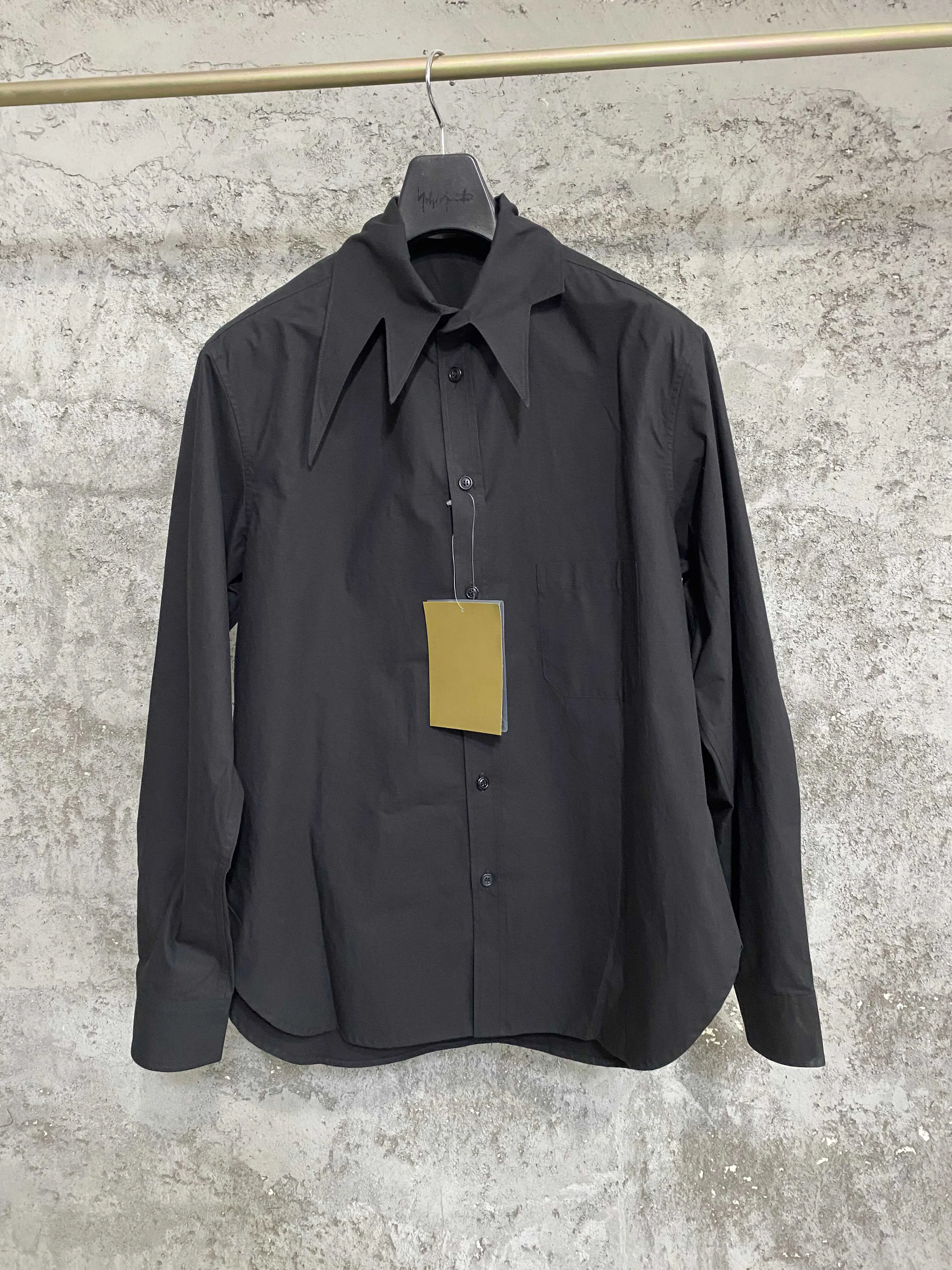 An independent designer of a long, dark leaf-collared shirt