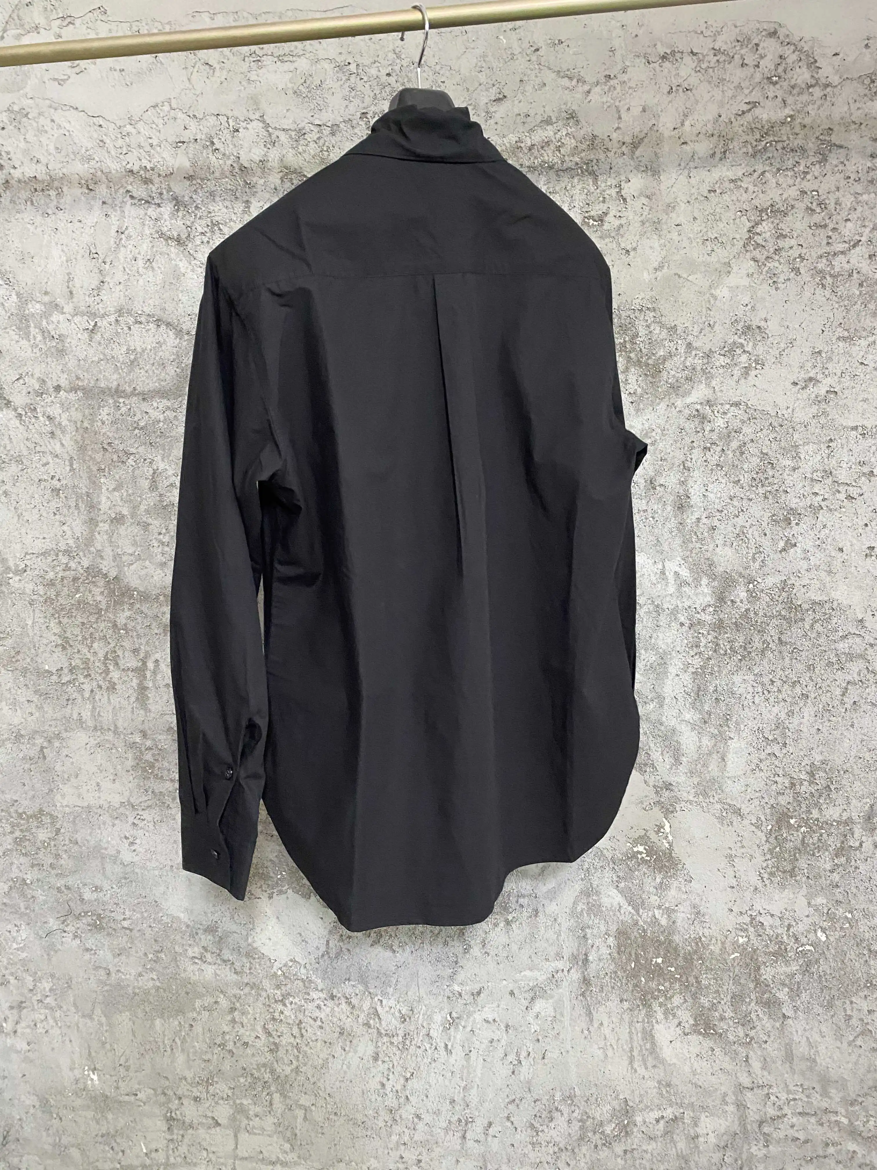 An independent designer of a long, dark leaf-collared shirt