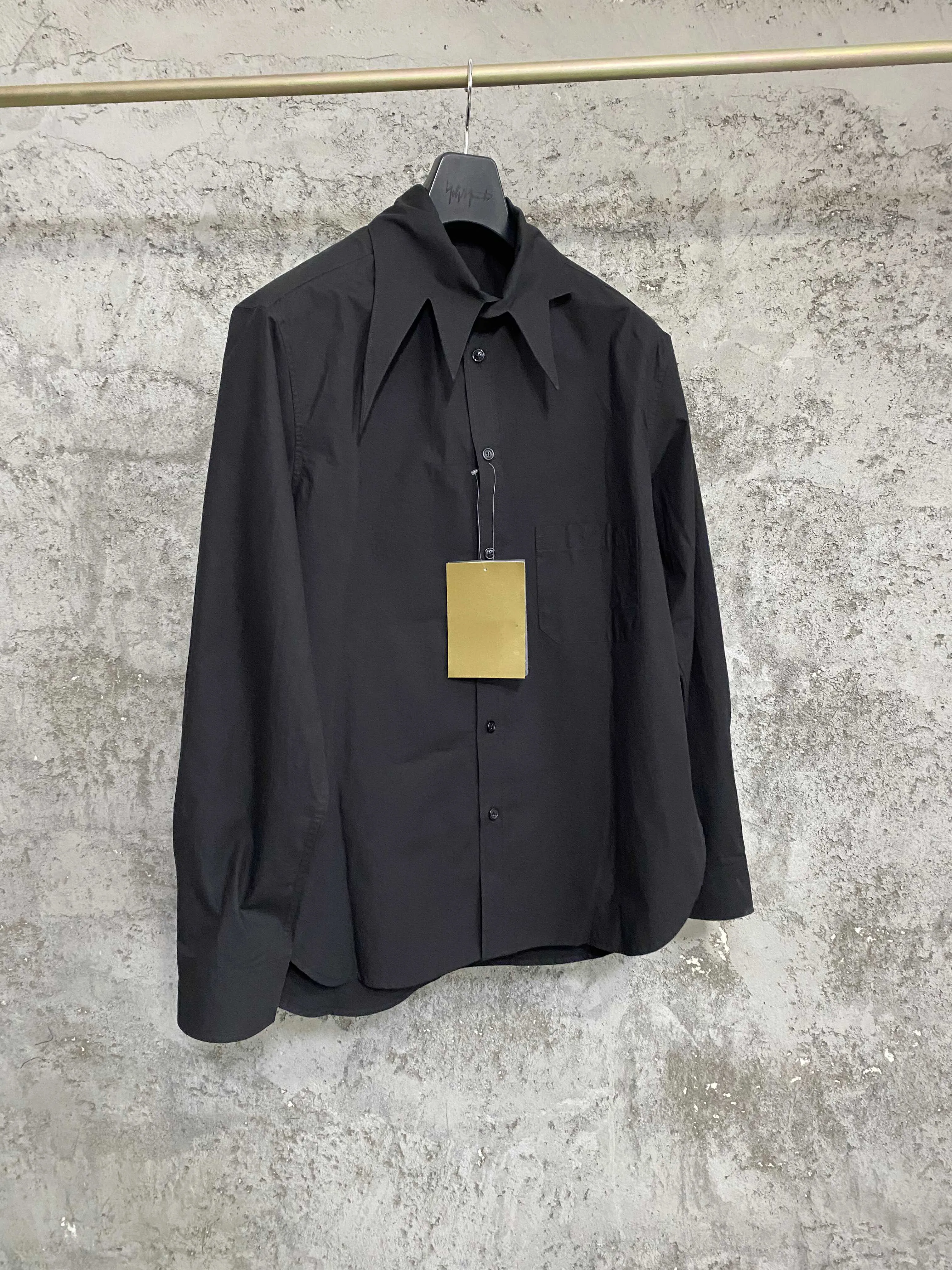 An independent designer of a long, dark leaf-collared shirt