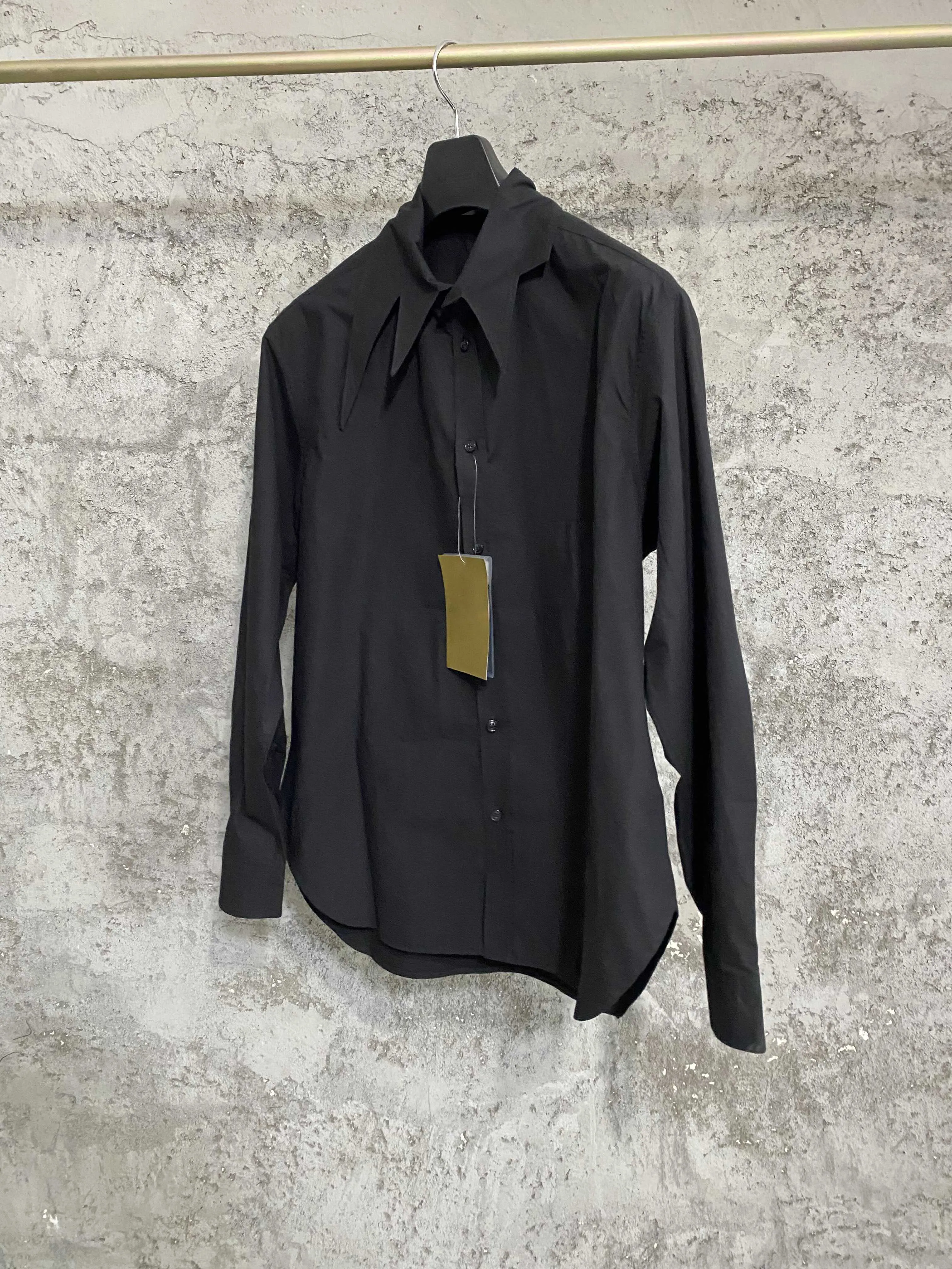 An independent designer of a long, dark leaf-collared shirt