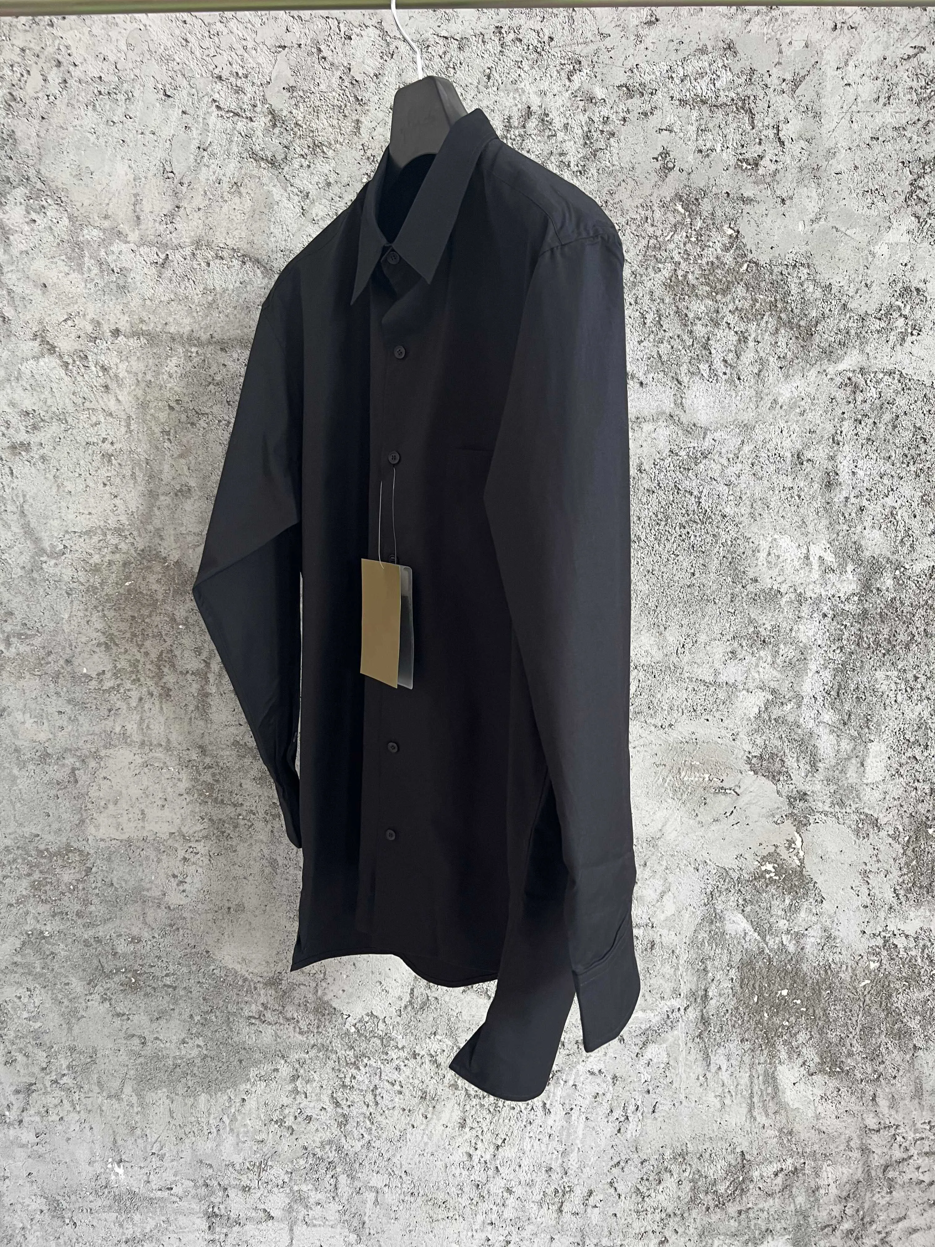 A simple long-sleeved single-breasted shirt with a double-layered collar, solid color and asymmetrical design